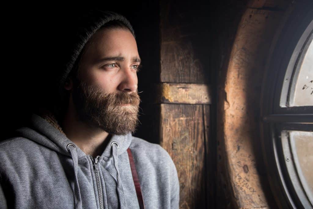 Man with beard looking out the window